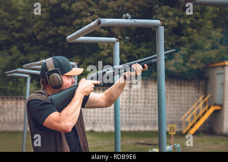 Vilnius, Lituanie - 25 août 2018 : un homme en casque insonorisées pousses avec un fusil sur un disque dur à plateaux de vol vue de côté. Banque D'Images