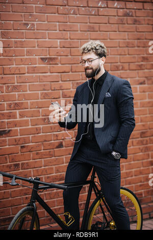 L'homme d'affaires barbu beau écouter de la musique en ville en vélo. Banque D'Images