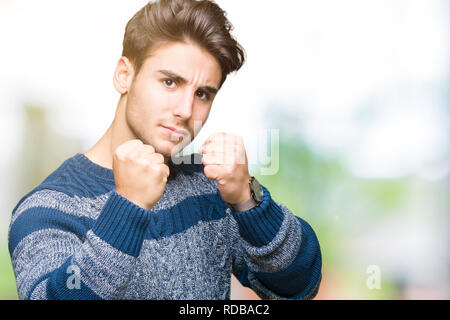 Jeune homme séduisant sur fond isolé prêt à combattre avec fist, geste de défense en colère et contrarié face, peur de problème Banque D'Images