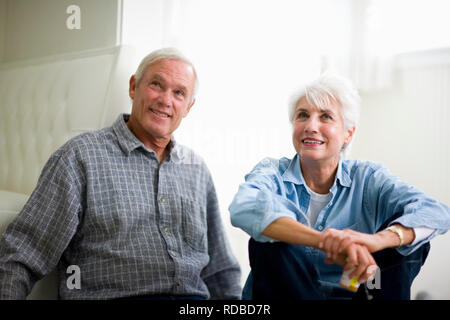 Adulte mature couple reading l'étiquette de la médecine tout en étant assis sur le plancher. Banque D'Images