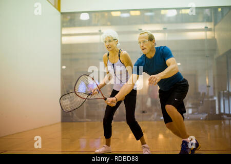 Senior woman et mid-adult man playing squash ensemble dans une cour de jeu. Banque D'Images