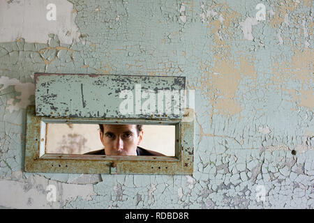 Portrait of a young woman à travers un trou dans un mur d'un bâtiment abandonné. Banque D'Images