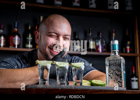 Barman pouring disque esprit dans de petits verres comme les coups de tequila ou de boisson forte Banque D'Images