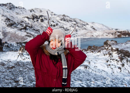 Girl holding des branches d'arbres gelés par le lac Banque D'Images