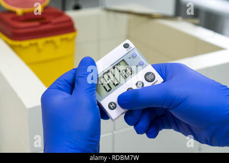 Dans les mains de girofle bleu tenant une horloge ou une minuterie de laboratoire Banque D'Images