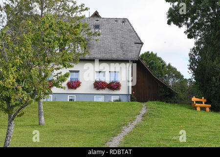 Vieille maison avec des fleurs à la fenêtre de dialogue et un banc en Forêt Noire Allemagne Banque D'Images