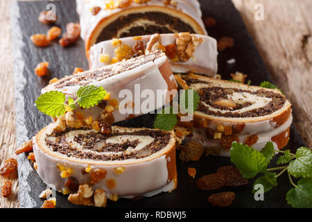 Gâteau aux Graines de pavot Noël tranchés en partie sur table en bois dans un style rustique. Banque D'Images