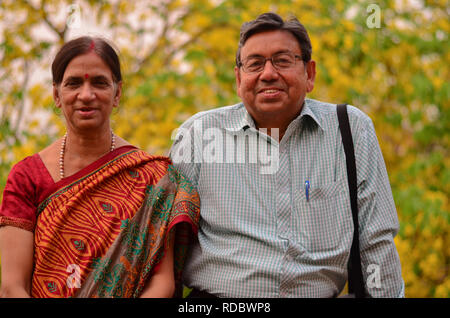Couple indien senior se tenant contre la douche jaune dorée amaltas feuilles pendant l'été d'automne à Delhi, Inde Banque D'Images