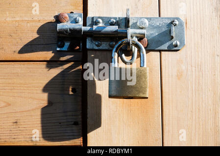 Cadenas en laiton avec anse en acier trempé assurant un boulon sur une cabane en bois des portes pour la sécurité. UK Banque D'Images