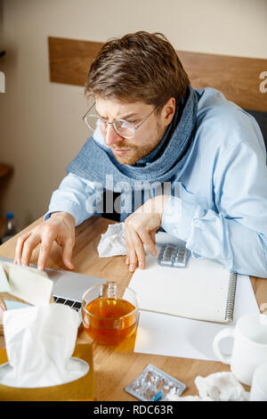 Se sentir malade et fatigué. L'homme avec une tasse de thé chaud working in office, homme d'affaires pris froid, la grippe saisonnière. La pandémie de grippe, la prévention des maladies, la climatisation au pouvoir provoquer la maladie Banque D'Images