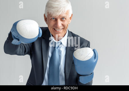 Vie d'entreprise. Businessman in boxing isolés sur joyeuse frapper gris Banque D'Images