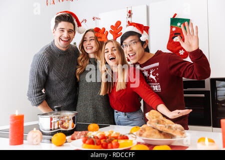 Groupe de personnes d'Europe et d'Asie la célébration de nouvelle année en chambre cuisine avec repas de vacances Banque D'Images