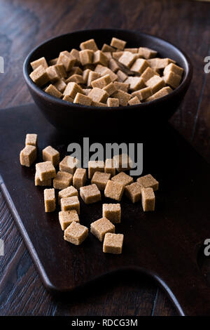 Cubes de sucre brun biologique de matières premières en bol en bois prêt à manger. Produit alimentaire. Banque D'Images