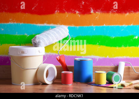 Outils de peinture sur parquet avec mur peint de diverses couleurs. Composition horizontale. Vue de face. Banque D'Images