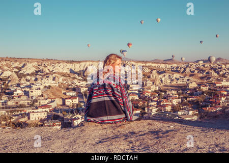 Jeune fille à l'aube à regarder les ballons et profiter de la vie. La Cappadoce, Uchisar, Turquie. Banque D'Images