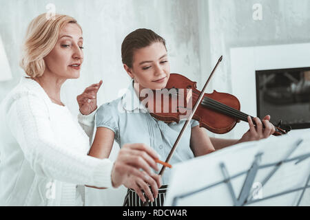 Femme d'un âge agréable montrant comment jouer Banque D'Images