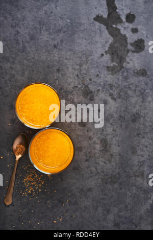 Boisson d'été. Jus d'orange en verre grand et la cuillère de sucre brun foncé sur fond de béton. Vue de dessus, copiez l'espace pour le texte. Focus sélectif. Banque D'Images