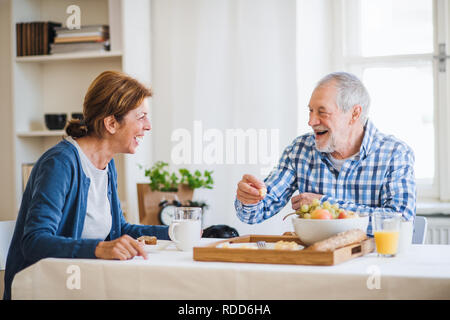 Un couple assis à la table à la maison, prendre le petit déjeuner. Banque D'Images