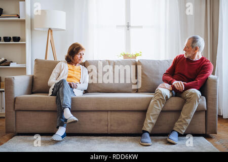 Un couple assis sur un canapé à la maison, ayant un argument. Banque D'Images