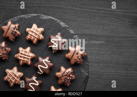 Chocolats en forme d'étoile sur fond texturé noir avec de l'espace texte Banque D'Images