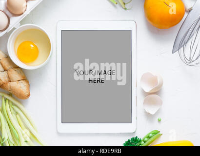 Digital touch screen tablet avec des légumes frais et des ustensiles de cuisine sur l'arrière-plan, Vue de dessus Banque D'Images