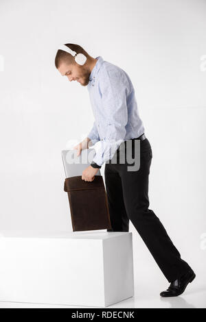 Businessman in headphones met dans le couvercle pour ordinateur portable Banque D'Images