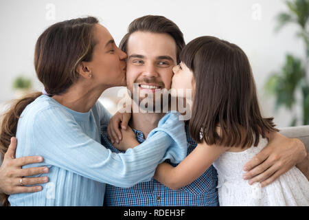 Kid fille et femme embrassant les baisers heureux père sur les joues Banque D'Images