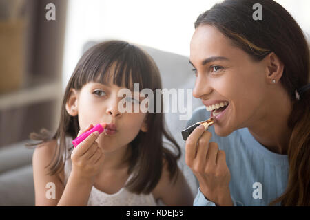 Heureuse maman et enfant fille ayant du plaisir ensemble maquillage Banque D'Images