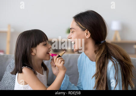 Maman souriant et heureux kid fille maquillage faire ensemble Banque D'Images