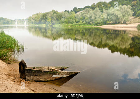 Un vieux bateau en bois la moitié submergé dans l'eau sur un matin d'été donnant sur la Misty bridge Banque D'Images