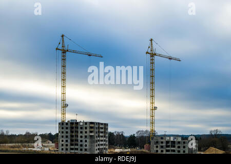Silhouette grues à tour et à plusieurs étages inachevé de hauts bâtiments en construction à jour nuageux Banque D'Images