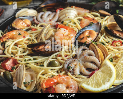 Pâtes cuites avec les palourdes, crevettes, moules, poulpes bébé tomate sur une poêle , spaghetti. Close up Banque D'Images