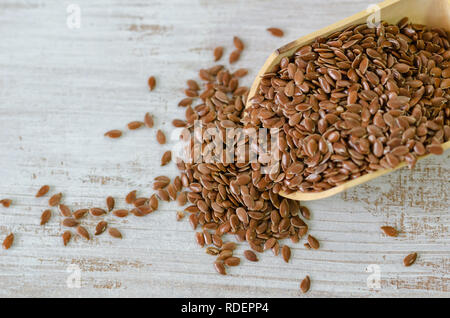 Graines de lin brun en cuillère en bois sur fond blanc. Banque D'Images