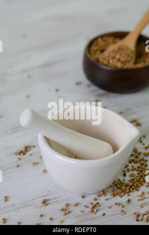 Les graines de coriandre dans un mortier en porcelaine sur la table en bois blanc, Banque D'Images