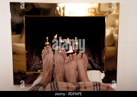 Close up image de couple sous la couverture par cheminée réchauffe pieds de cabin home dans les vacances d'hiver froid à happy moments romantiques Banque D'Images