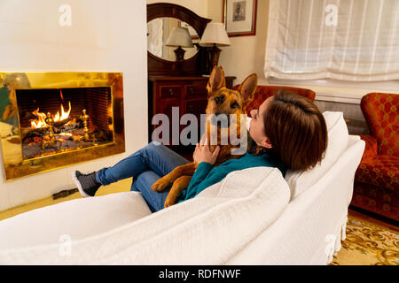 Magnifique portrait of smiling woman hugging son chien berger allemand ensemble devant le foyer à l'accueil chaleureux dans la journée d'hiver de bonheur l'Amitié Banque D'Images