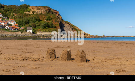 Châteaux de sable sur la plage de sables bitumineux, Runswick North Yorkshire, Angleterre Royaume-uni - Runswick Bay avec en arrière-plan Banque D'Images