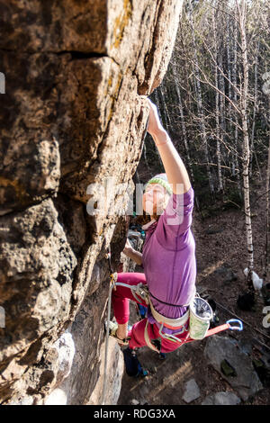 Girl rock climber grimpe sur le rocher avec la réduction de la prime d'hommes dans des vêtements colorés et un chapeau à l'automne. Banque D'Images