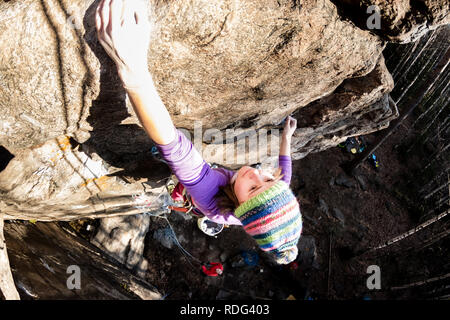 Girl rock climber grimpe sur le rocher avec la réduction de la prime d'hommes dans des vêtements colorés et un chapeau à l'automne. Banque D'Images