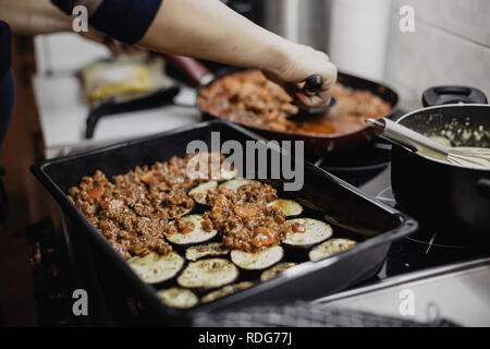 La moussaka plat européen en cours de préparation dans la cuisine par femme Banque D'Images