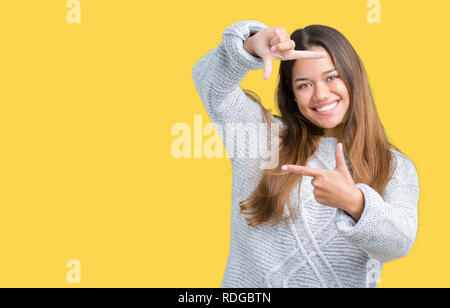 Jeune belle brunette woman wearing sweater sur fond isolé du châssis en souriant avec les mains et les doigts avec un visage heureux. La créativité et le ph Banque D'Images