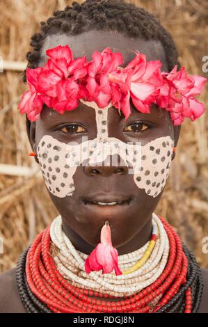 Karo fille avec un bandeau à fleurs, peintures faciales, colliers colorés et piercing lèvre, portrait, vallée de la rivière Omo Banque D'Images