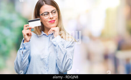 Young beautiful business woman holding credit card sur fond isolé visage sérieux de penser à question, idée très confus Banque D'Images