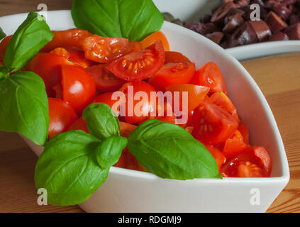 Tasse en céramique blanche avec tomates et basilic frais haché, en tranches olives ​​Black sur l'arrière-plan Banque D'Images