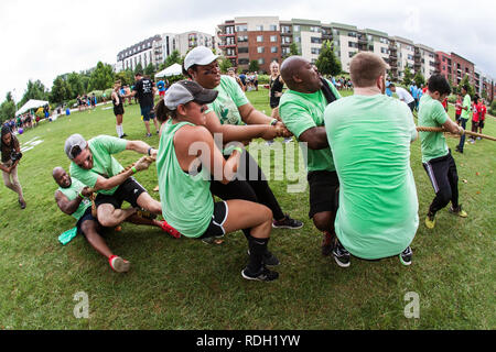 Une équipe de jeunes adultes, hommes et femmes luttent pour tirer la corde qu'ils sont en concurrence dans un concours de tir à la corde pendant une journée sur le terrain d'Atlanta le 14 juillet 2018. Banque D'Images