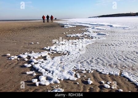 Les gens qui marchent le long de la plage couverte de neige sur la Frise orientale Mer du Nord île de Spiekeroog, Basse-Saxe Banque D'Images