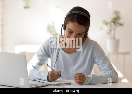 Happy smiling woman in headphones écrit dans l'ordinateur portable Banque D'Images