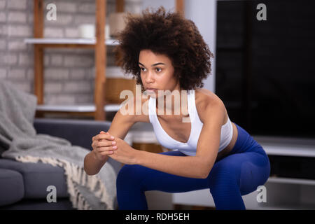 Jeune femme en faisant porter l'exercice Fitness Squat à la maison Banque D'Images