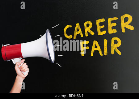 A person's Hand Holding Megaphone près de Yellow Career Fair Texte sur fond noir Banque D'Images