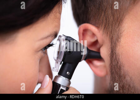 Female Doctor Examining patient de sexe masculin avec l'oreille d'un otoscope Banque D'Images